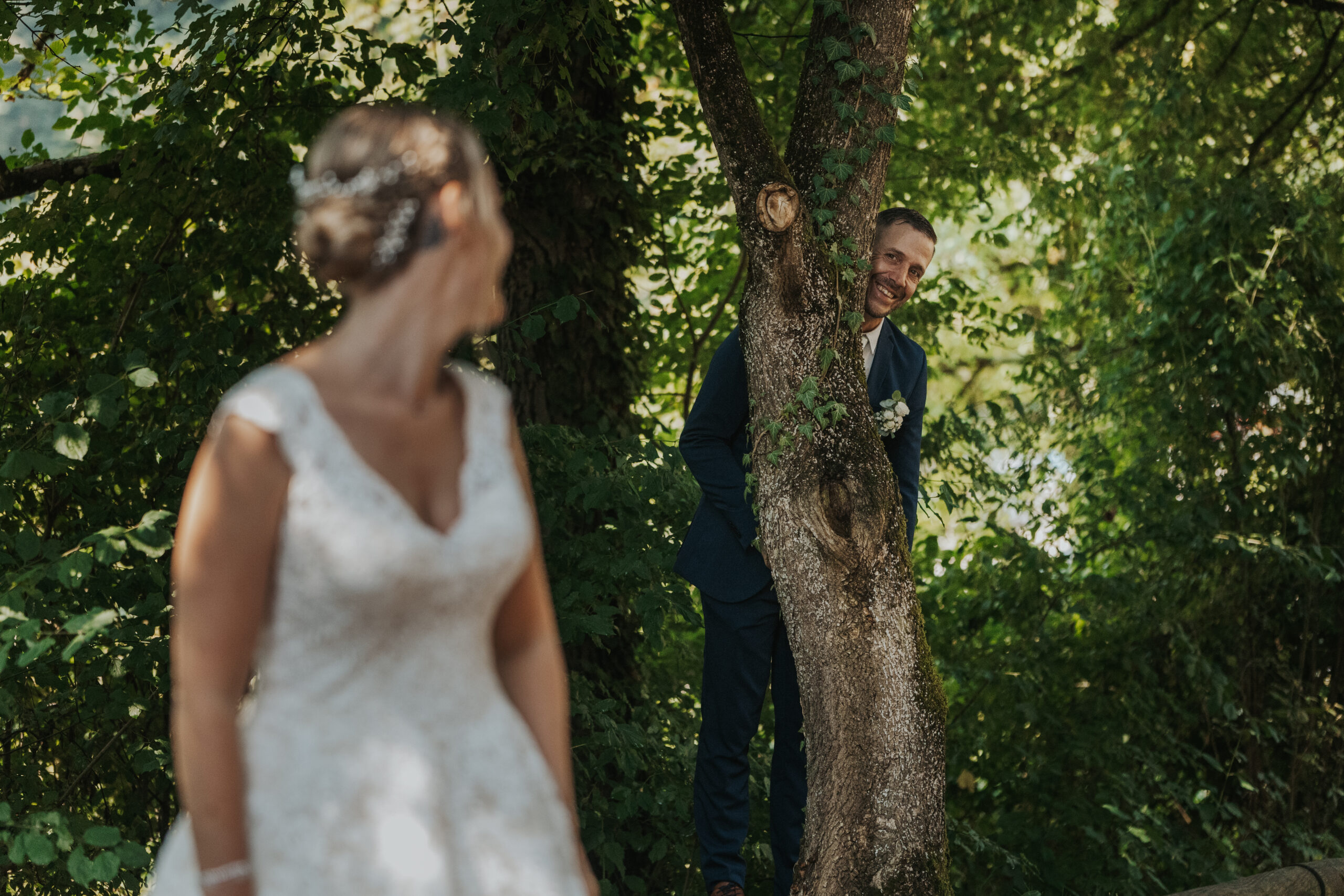 Amüsante Hochzeitsideen auf Burg Rötteln, Mann versteckt sich hinter dem Baum vor seiner Braut, fotografiert durch Kameralaus.